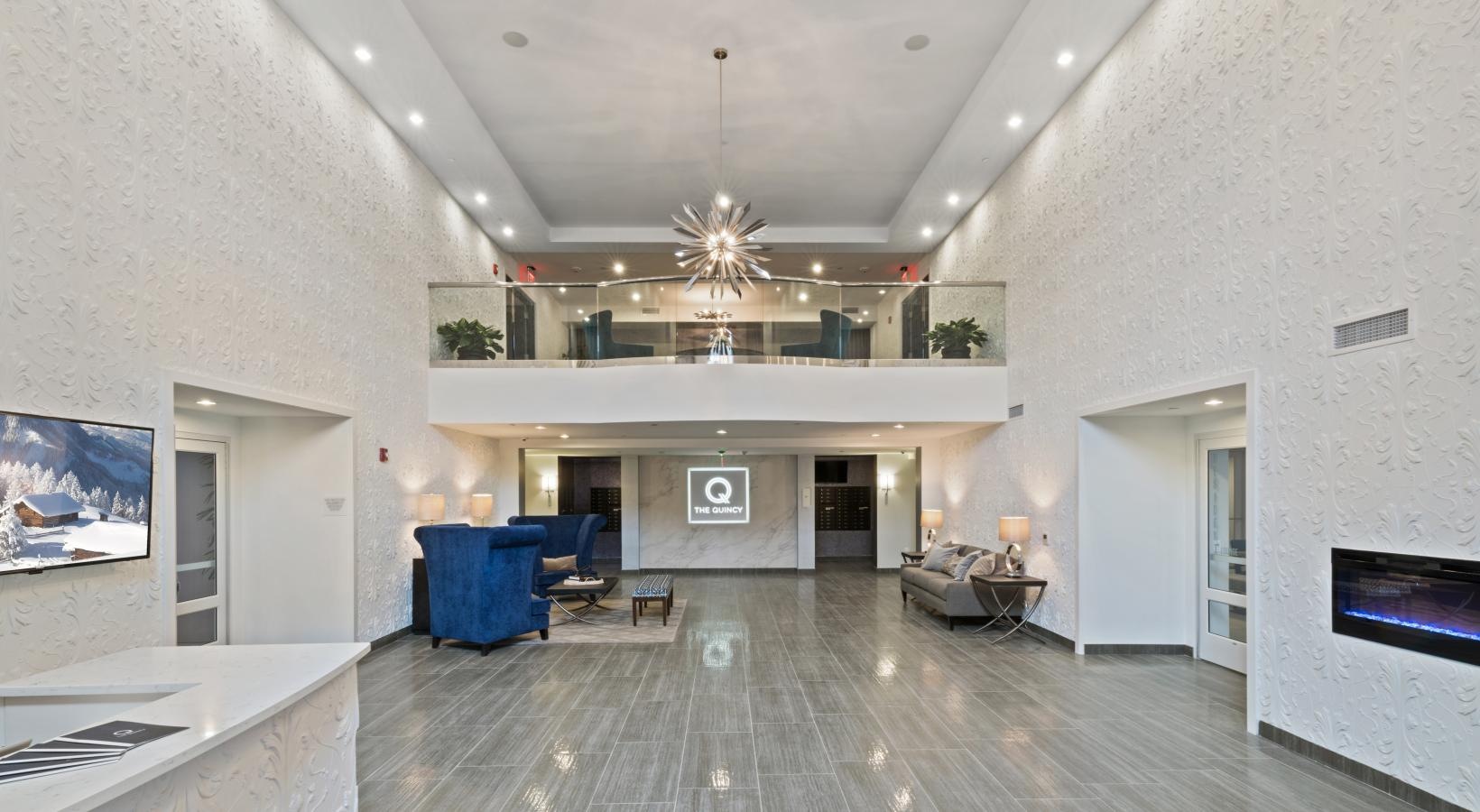Settle into comfort at The Quincy a large room with a wood floor and a white ceiling